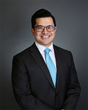 Professional headshot of Dr. Tokuhara smiling in a suit